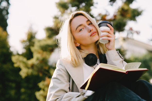 Rubia sentada en un pasto con auriculares