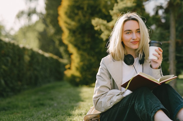 Rubia sentada en un pasto con auriculares