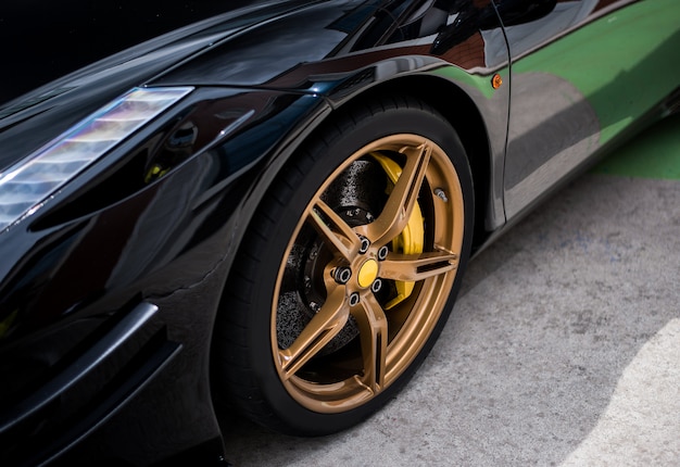 Rueda de coche sedán negro con decoración en color dorado y bronce.