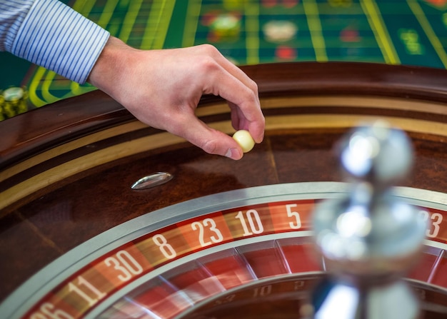 Foto gratuita rueda de la ruleta y mano del crupier con bola blanca en el casino detalles de primer plano