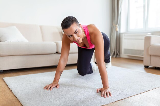 Rutina de entrenamiento Una mujer negra atlética activa haciendo ejercicio de escaladores de montaña en una alfombra de yoga fuerte mujer deportiva en ropa deportiva entrenando músculos abdominales en el gimnasio o en casa