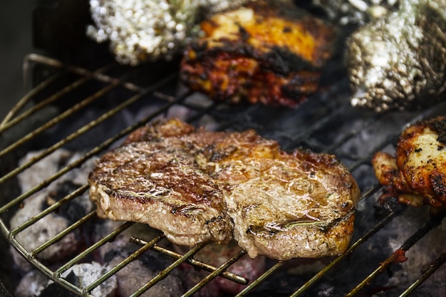 Sabrosa carne de carne apetitosa fresca en la parrilla de cocina en el fuego abierto en la rejilla de la parrilla. Fondo De La Naturaleza. De cerca.