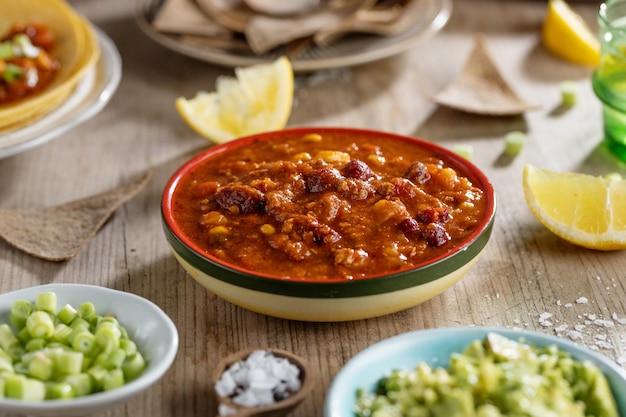 Sabrosa comida mexicana con salsa de aguacate fresco burittos tacos chili con carne en mesa de madera