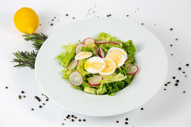 Sabrosa ensalada con rábano lechuga y huevos sobre un blanco