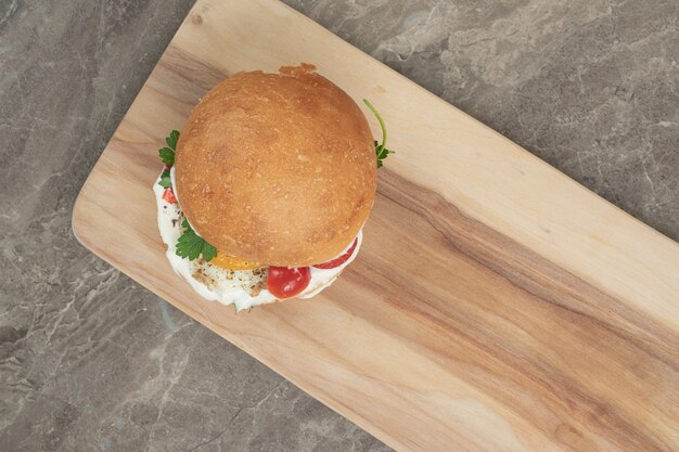 Sabrosa hamburguesa con huevo frito sobre tabla de madera. Foto de alta calidad
