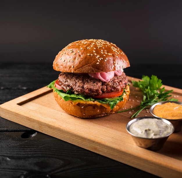 Foto gratuita sabrosa hamburguesa con queso en una tabla de madera lista para ser servida