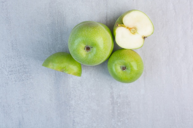 Sabrosa manzana verde entera y en rodajas, sobre el mármol.