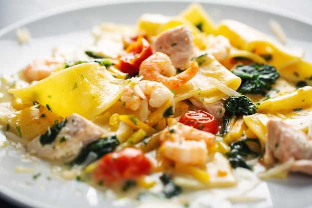 Sabrosa pasta apetitosa con camarones, verduras y espinacas servido en plato.