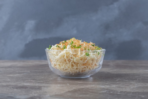 Sabrosa pasta de fideos con verdura verde en el cuenco, sobre la superficie de mármol.