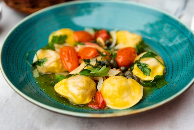 Sabrosa pasta de ravioles en plato de cerámica verde