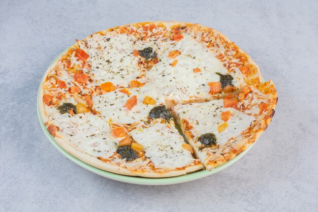 Sabrosa pizza con pepinos salados y queso sobre un fondo blanco.