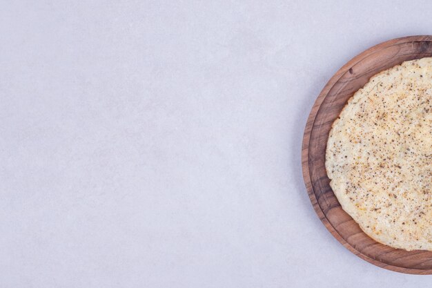 Sabrosa pizza en placa de madera sobre superficie blanca
