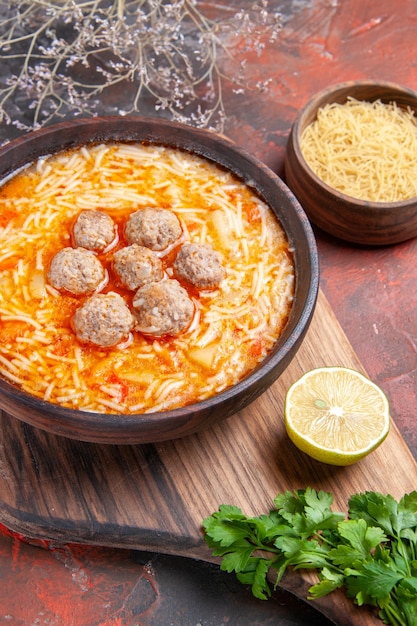 Sabrosa sopa de albóndigas con fideos a bordo de pasta de madera de limón un montón de verduras en el metraje de la mesa oscura