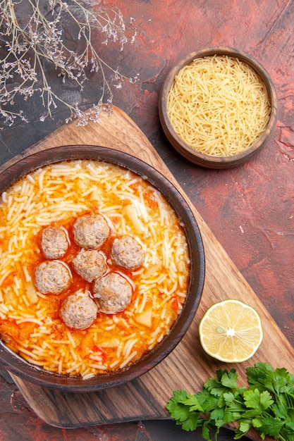 Sabrosa sopa de albóndigas con fideos a bordo de pasta de madera de limón un montón de verduras sobre fondo oscuro