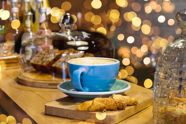 Sabrosa taza de café con leche en una mesa de madera en una cafetería luces bokeh en el fondo