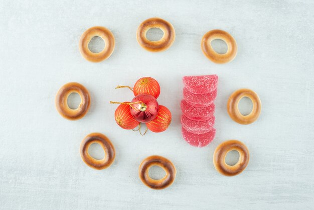 Sabrosas galletas dulces redondas con bolas de Navidad rojas sobre fondo blanco. Foto de alta calidad