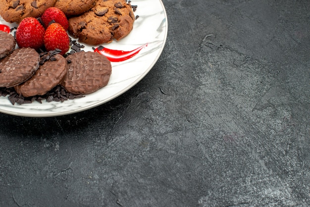 Sabrosas galletas de media vista superior con trozos de chocolate y jugosas fresas con espacio libre