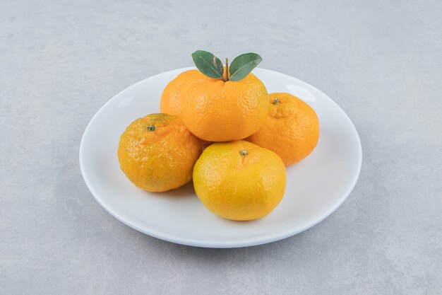 Sabrosas mandarinas frescas en plato blanco