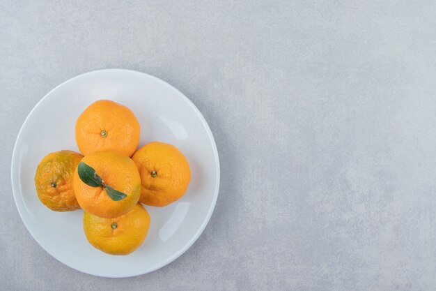 Sabrosas mandarinas frescas en plato blanco