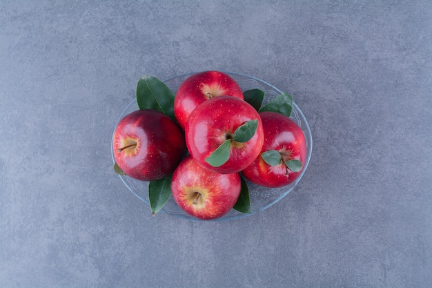 Sabrosas manzanas en una placa de vidrio sobre una mesa de mármol.