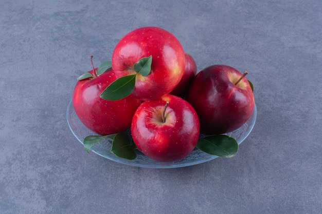 Sabrosas manzanas en una placa de vidrio sobre la superficie oscura