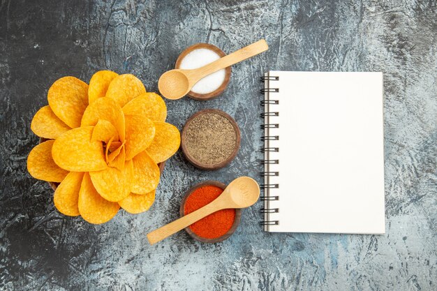 Sabrosas patatas fritas decoradas como diferentes especias en forma de flor con cucharas sobre fondo gris