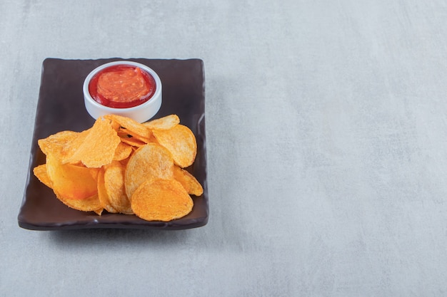 Foto gratuita sabrosas patatas fritas con especias y salsa de tomate colocadas en un plato oscuro.