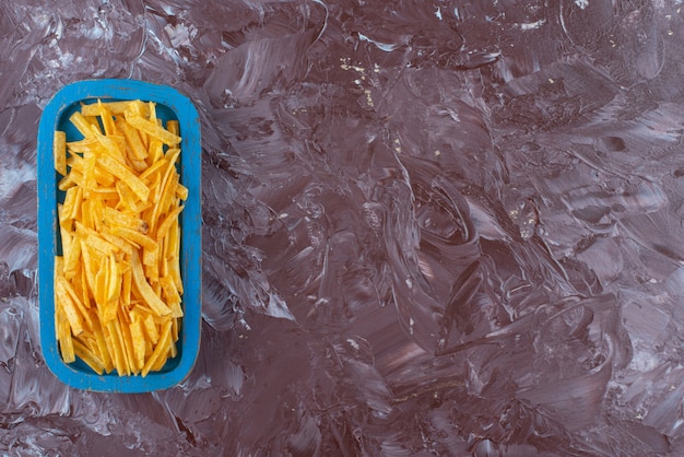 Sabrosas patatas fritas en una placa de madera, sobre la mesa de mármol.