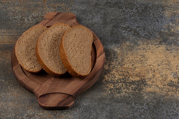 Sabrosas rebanadas de pan negro sobre tabla de madera