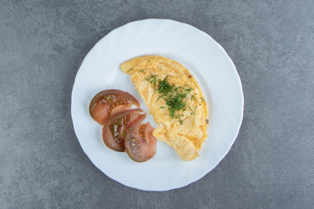 Sabrosas rodajas de tortilla y tomate en un plato blanco.