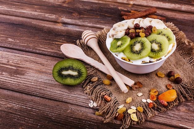 Sabroso desayuno saludable por la mañana hecho de leche y gachas de avena con nueces, kiwis y miel