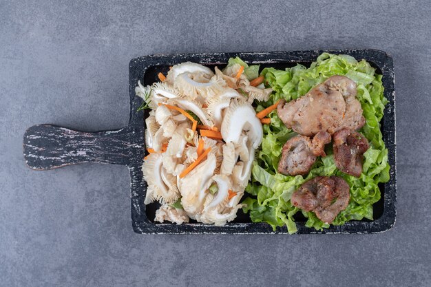 Sabroso kebab a la parrilla y ensalada de verduras sobre tabla de madera.