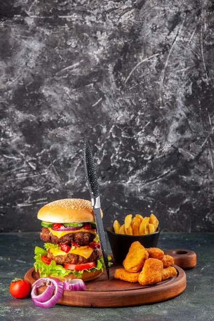 Sabroso sándwich casero tomates pimiento sobre tabla de cortar de madera cebollas tomate con tallo nuggets de pollo papas fritas sobre superficie de color oscuro