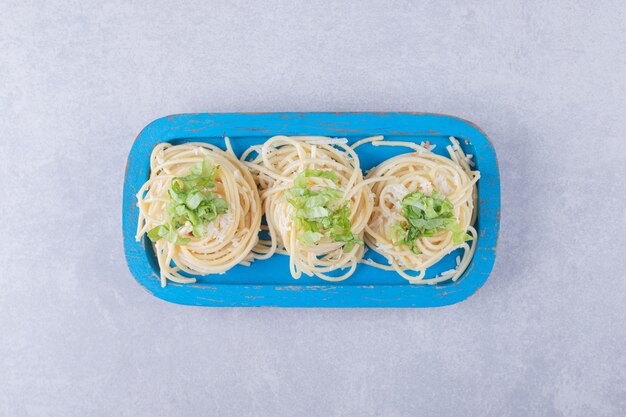 Sabrosos espaguetis hervidos con verduras en placa azul.