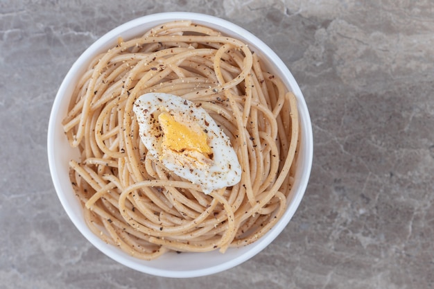 Sabrosos espaguetis con huevo en un tazón blanco.