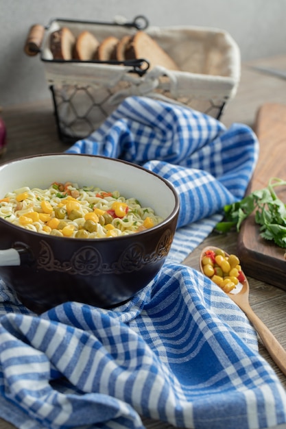 Foto gratuita sabrosos fideos con guisantes y maíz y canasta de rebanadas de pan