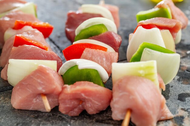 Sabrosos pinchos de carne cruda apetitosos sobre fondo de piedra oscura. De cerca