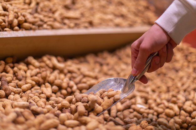 Sacando cacahuetes del stock en el supermercado. Foto de alta calidad