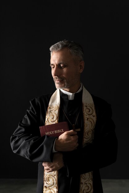 Sacerdote cristiano de tiro medio sosteniendo la biblia