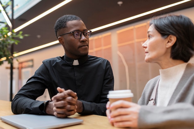 Foto gratuita sacerdote masculino joven con adoradora femenina en un café