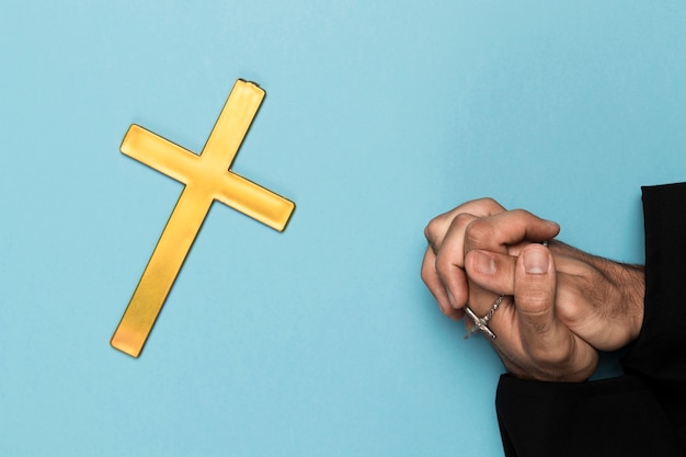 Sacerdote rezando con cruz de madera