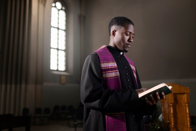 Sacerdote de sexo masculino joven con una biblia en iglesia