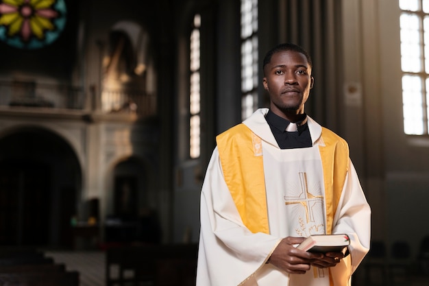 Sacerdote de sexo masculino joven con una biblia en iglesia