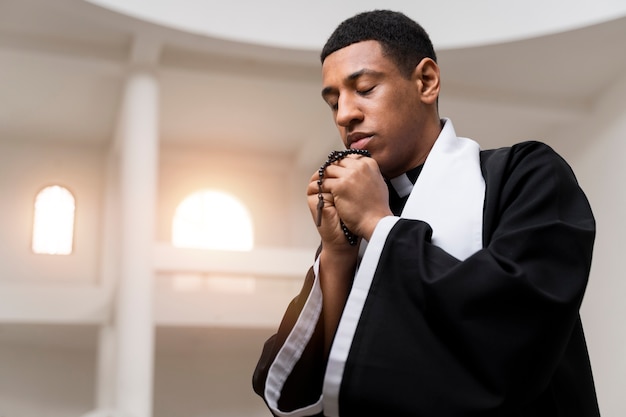 Foto gratuita sacerdote de tiro medio rezando con cruz.