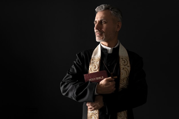 Foto gratuita sacerdote de tiro medio sosteniendo la biblia