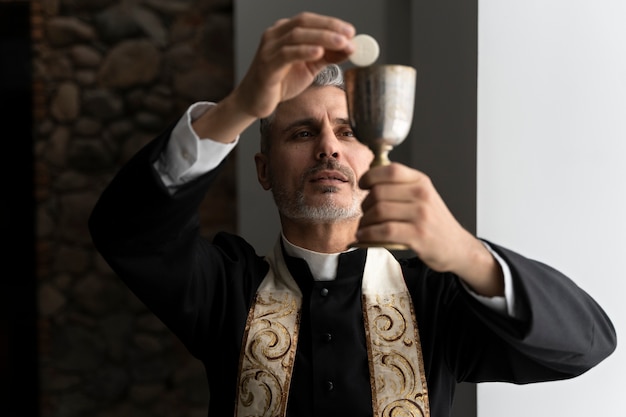 Sacerdote de tiro medio sosteniendo la eucaristía