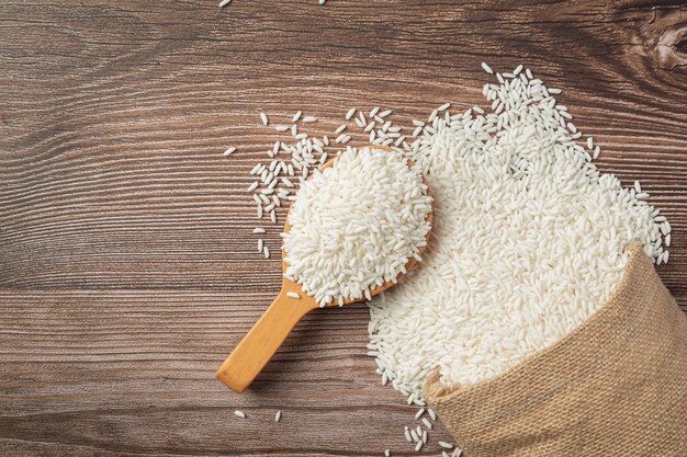 Saco de arroz blanco y cuchara de madera en un piso de madera