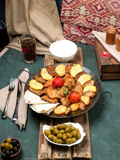 Foto gratuita saco ichi caucásico con carne y papas servidas con yogurt y composto sobre una tabla de madera