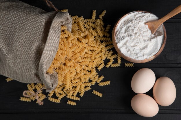 Un saco lleno de fusilli de pasta seca cruda con harina y huevos de gallina. Foto de alta calidad