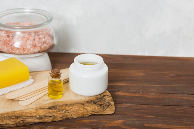 Sal de Himalaya en tarro de vidrio; palos de madera de cera; miel; Jabón amarillo herbal y botella de aceite esencial en mesa.